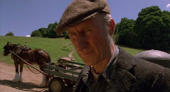 Movie still from “Babe” (1995), directed by Chris Noonan – An older man wearing a hat standing in front of a horse drawn carriage; Close Up shot, Low angle