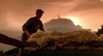 Movie still from “Babe” (1995), directed by Chris Noonan – A man standing on top of a pile of wool; Wide shot, Low angle