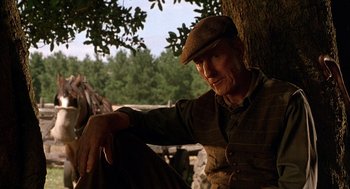 Movie still from “Babe” (1995), directed by Chris Noonan – An old man sitting on a tree in a forest; Close Up shot, Low angle