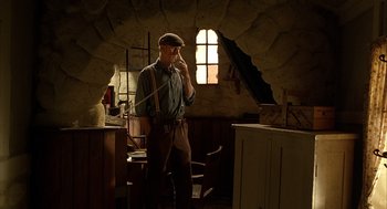 Movie still from “Babe” (1995), directed by Chris Noonan – A man standing in a room holding a cell phone to his ear; Medium shot, Low angle