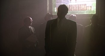 Movie still from “Babe” (1995), directed by Chris Noonan – A group of men standing in front of a stained glass window; Medium shot, Low angle