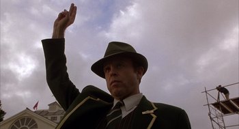 Movie still from “Babe” (1995), directed by Chris Noonan – A man wearing a hat and a suit raising his hand; Close Up shot, Low angle