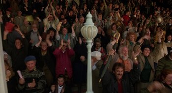 Movie still from “Babe” (1995), directed by Chris Noonan – A crowd of people sitting and standing in front of a street light; Wide shot, High angle