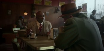 Movie still from “Fargo” (2014), created by Noah Hawley – Two men are sitting at a table in a restaurant; Medium shot, Over the shoulder angle