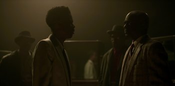 Movie still from “Fargo” (2014), created by Noah Hawley – A group of men standing next to each other in a dark room; Medium shot, Over the shoulder angle