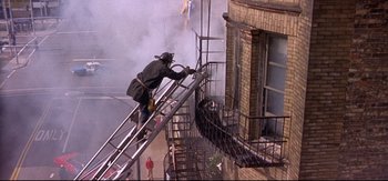 Movie still from “Backdraft” (1991), directed by Ron Howard – A man on a fire truck that is on a fire escape; Wide shot, Low angle