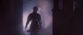 Movie still from “Backdraft” (1991), directed by Ron Howard – A fire fighter is standing in the fog; Medium shot, Low angle