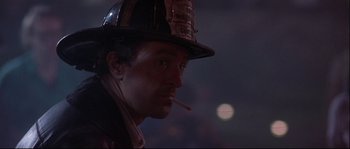 Movie still from “Backdraft” (1991), directed by Ron Howard – A man in a fireman's hat smoking a cigarette; Close Up shot, Low angle