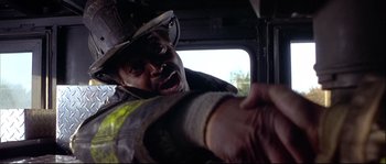 Movie still from “Backdraft” (1991), directed by Ron Howard – A man in a fireman's uniform is holding his hand out to someone; Close Up shot, Low angle