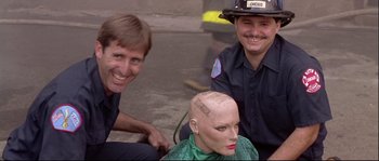 Movie still from “Backdraft” (1991), directed by Ron Howard – A man sitting next to two firemen with a bald head; Close Up shot, Over the shoulder angle