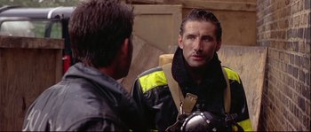 Movie still from “Backdraft” (1991), directed by Ron Howard – A man in a black jacket is talking to another man; Close Up shot, Over the shoulder angle
