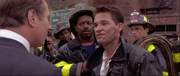 Movie still from “Backdraft” (1991), directed by Ron Howard – A group of men standing next to each other on a street; Close Up shot, Over the shoulder angle