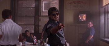 Movie still from “Backdraft” (1991), directed by Ron Howard – A man wearing sunglasses and a police uniform; Medium shot, Low angle
