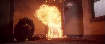 Movie still from “Backdraft” (1991), directed by Ron Howard – A fireman is sitting in front of an open fire door; Medium shot, Low angle