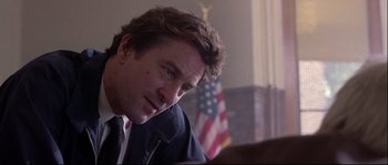 Movie still from “Backdraft” (1991), directed by Ron Howard – A person sitting in front of an american flag; Close Up shot, Low angle