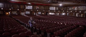 Movie still from “Backdraft” (1991), directed by Ron Howard – A person in a large auditorium with rows of chairs; Extreme Wide shot, High angle