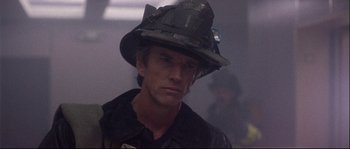 Movie still from “Backdraft” (1991), directed by Ron Howard – A man wearing a fireman's hat in a building; Close Up shot, Low angle