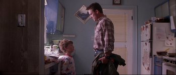 Movie still from “Backdraft” (1991), directed by Ron Howard – A man and a boy are standing in a room; Medium shot, Over the shoulder angle