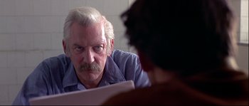 Movie still from “Backdraft” (1991), directed by Ron Howard – An older man sitting in front of another man; Close Up shot, Over the shoulder angle