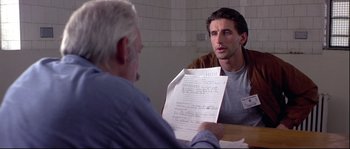 Movie still from “Backdraft” (1991), directed by Ron Howard – A man sitting in front of another man at a table holding papers; Close Up shot, Over the shoulder angle