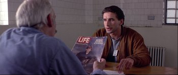 Movie still from “Backdraft” (1991), directed by Ron Howard – A man sitting in front of a man holding a magazine; Close Up shot, Over the shoulder angle