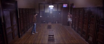 Movie still from “Backdraft” (1991), directed by Ron Howard – Two men standing in an empty room in front of a television; Wide shot, High angle