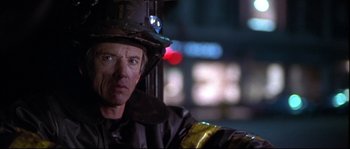 Movie still from “Backdraft” (1991), directed by Ron Howard – A man in a fireman's uniform sitting in front of a street light; Close Up shot, Over the shoulder angle