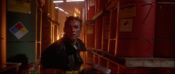 Movie still from “Backdraft” (1991), directed by Ron Howard – A man in a warehouse with lots of boxes behind him; Close Up shot, Low angle
