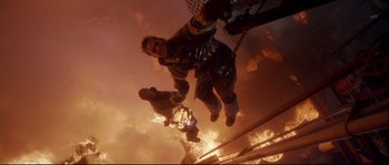 Movie still from “Backdraft” (1991), directed by Ron Howard – A man hanging from a rope while holding onto a chain; Wide shot, Low angle