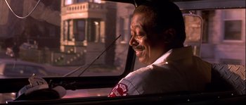 Movie still from “Backdraft” (1991), directed by Ron Howard – A man sitting in the back seat of a car looking out the window; Close Up shot, Low angle