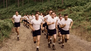 Movie still from “Band of Brothers” (2001), directed by David Frankel – A large group of men running on a dirt road; Wide shot, High angle