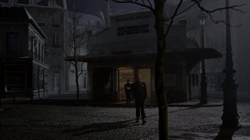 Movie still from “Band of Brothers” (2001), directed by David Frankel – A man standing in the dark in front of a building; Extreme Wide shot, High angle