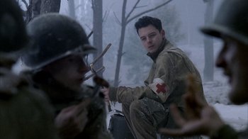 Movie still from “Band of Brothers” (2001), directed by David Frankel – A man sitting on top of a motorcycle in the snow; Medium shot, Over the shoulder angle