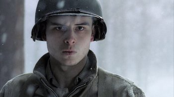 Movie still from “Band of Brothers” (2001), directed by David Frankel – A man wearing a helmet in the snow looking at the camera; Close Up shot, Low angle