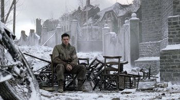 Movie still from “Band of Brothers” (2001), directed by David Frankel – A man sitting on a chair in the middle of a snowy field; Wide shot, High angle