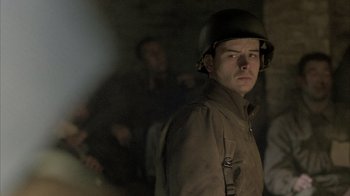 Movie still from “Band of Brothers” (2001), directed by David Frankel – A man in a military uniform and helmet; Close Up shot, Over the shoulder angle