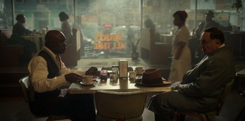 Movie still from “Fargo” (2014), created by Noah Hawley – Two people sitting at a table in front of a window; Medium shot, Over the shoulder angle