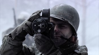 Movie still from “Band of Brothers” (2001), directed by David Frankel – A man holding a video camera while wearing gloves and a helmet; Extreme Close Up shot, High angle