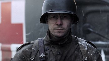 Movie still from “Band of Brothers” (2001), directed by David Frankel – A man wearing a military uniform and a helmet; Close Up shot, Low angle