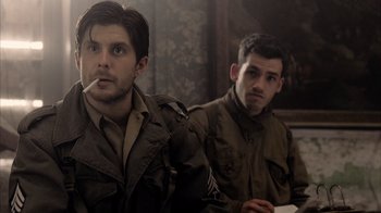 Movie still from “Band of Brothers” (2001), directed by David Frankel – Two young men in military fatigues sitting next to each other; Medium shot, Over the shoulder angle