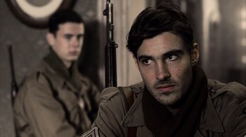 Movie still from “Band of Brothers” (2001), directed by David Frankel – A man with a gun in front of another man; Close Up shot, Over the shoulder angle