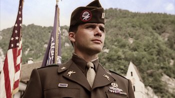 Movie still from “Band of Brothers” (2001), directed by David Frankel – A man in a military uniform standing in front of a flag; Close Up shot, Low angle
