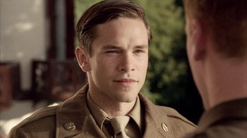 Movie still from “Band of Brothers” (2001), directed by David Frankel – A young man in a military uniform looks at the camera; Close Up shot, Over the shoulder angle