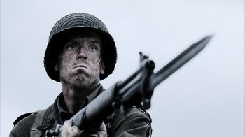 Movie still from “Band of Brothers” (2001), directed by David Frankel – A man holding a rifle while wearing an army uniform; Close Up shot, Low angle