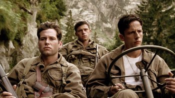 Movie still from “Band of Brothers” (2001), directed by David Frankel – A group of men sitting next to each other on top of a hill; Medium shot, Low angle