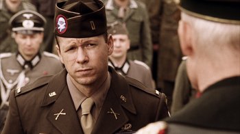 Movie still from “Band of Brothers” (2001), directed by David Frankel – A man in a military uniform is standing in front of a group of men; Close Up shot, Over the shoulder angle
