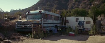 Movie still from “Band of Robbers” (2015), directed by Adam Nee – An old school bus parked in the dirt; Extreme Wide shot, High angle