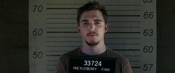 Movie still from “Band of Robbers” (2015), directed by Adam Nee – A man in a brown shirt is in front of a white wall; Close Up shot, High angle