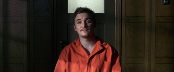 Movie still from “Band of Robbers” (2015), directed by Adam Nee – A man in an orange shirt standing in front of a door; Close Up shot, High angle