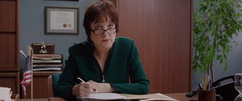 Movie still from “Band of Robbers” (2015), directed by Adam Nee – A woman sitting at a table writing on a piece of paper; Close Up shot, Over the shoulder angle